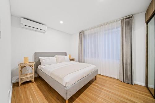 a white bedroom with a bed and a window at Scarborough Escape, New 2Br Suite, 14G in Perth