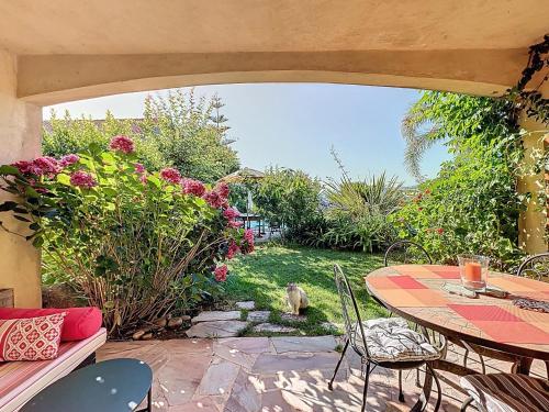 a patio with a table and chairs and flowers at Petit coin de paradis, vue panoramique mer &montagne, piscine privée... in Calcatoggio