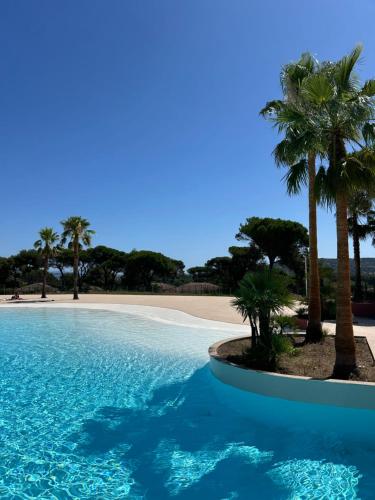 - une piscine bordée de palmiers et une plage dans l'établissement Charmante maison californienne - jacuzzi - piscine dans le domaine - Golfe de St Tropez - 6-8 personnes, à Gassin