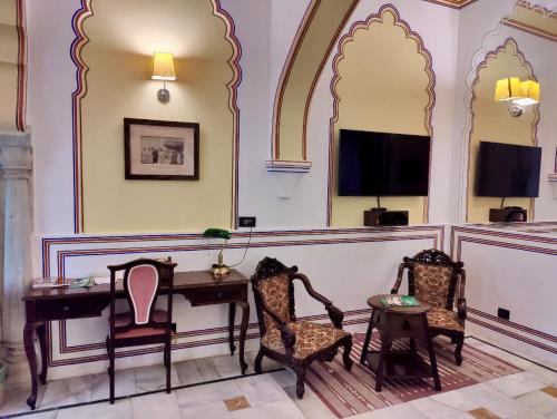 a waiting room with chairs and a desk and a tv at Hotel Narain Niwas Palace in Jaipur