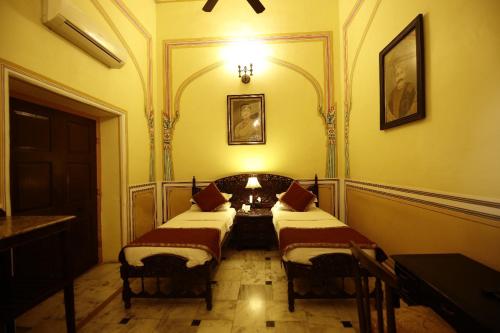 a room with two beds and a table in it at Hotel Narain Niwas Palace in Jaipur