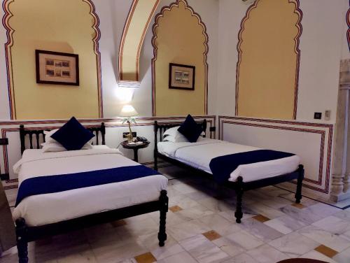 a room with two beds in a room at Hotel Narain Niwas Palace in Jaipur