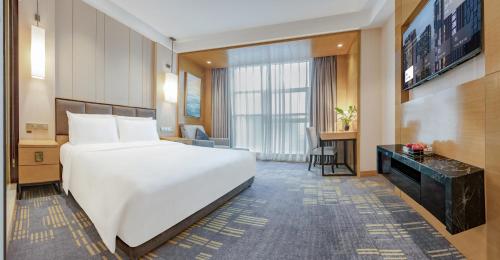 a hotel room with a white bed and a television at Lyhn International Hotel Chengdu Taikoo Li in Chengdu