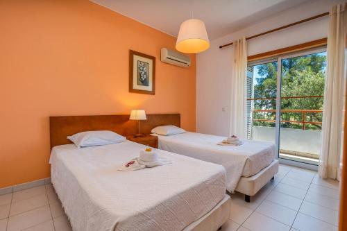 due letti in una stanza con finestra di Apartamentos Santa Teresinha ad Alvor