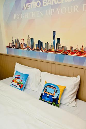 a bed with two pillows on it with a city backdrop at Metro Hotel Phahonyothin 35 in Bangkok