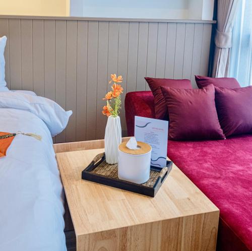 a bed room with a table with a vase of flowers at Metro Hotel Phahonyothin 35 in Bangkok