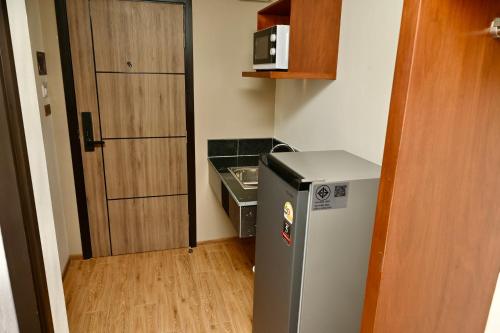 a small kitchen with a refrigerator next to a door at Metro Hotel Phahonyothin 35 in Bangkok