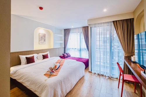 a hotel room with a large bed with a table at Metro Hotel Phahonyothin 35 in Bangkok
