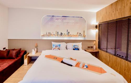 a bedroom with a large white bed and a red couch at Metro Hotel Phahonyothin 35 in Bangkok