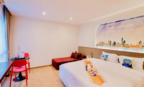 a hotel room with a large bed and a desk at Metro Hotel Phahonyothin 35 in Bangkok