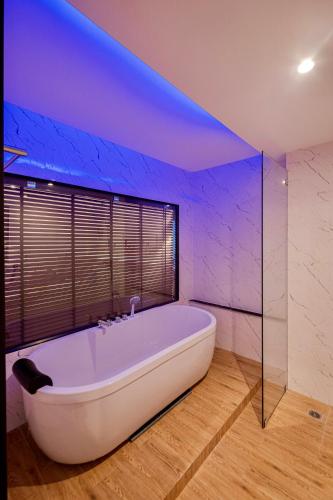 a white bath tub in a bathroom with a blue lighting at Metro Hotel Phahonyothin 35 in Bangkok