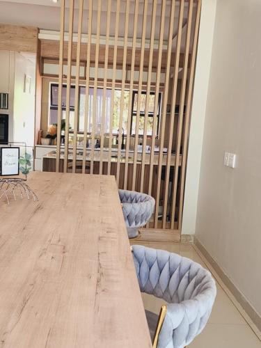 a large wooden table with two blue chairs in a room at Eastern Road Executive Suites in Harare
