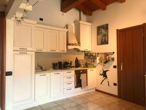a white kitchen with white cabinets and a door at La casa rossa in Costa Volpino