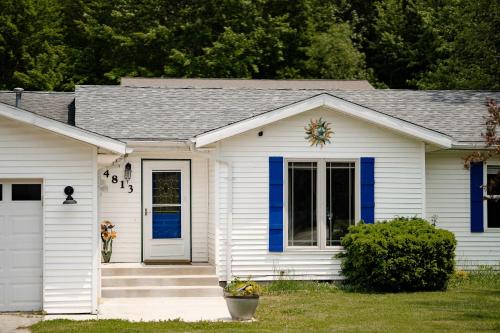 a white house with blue trim and a door at Kevins Place near PawPaw Lake in Watervliet