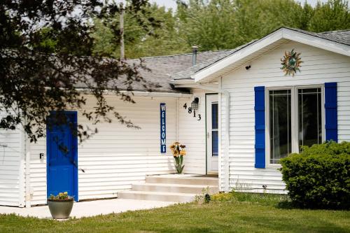 a white house with a blue door and stairs at Kevins Place near PawPaw Lake in Watervliet