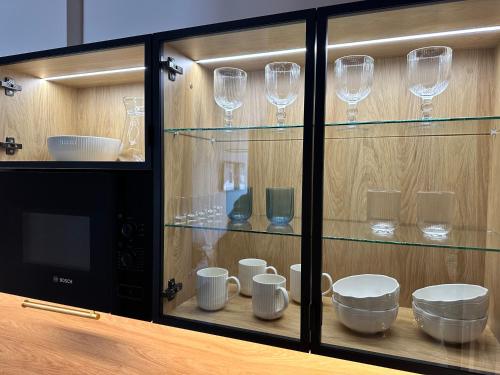 a glass cabinet with cups and dishes in it at NOWE !!! Apartamenty OFF PIOTRKOWSKA w Roosevelta Residence, Klimatyzacja, Wejście na KOD, WiFi, FV in Łódź
