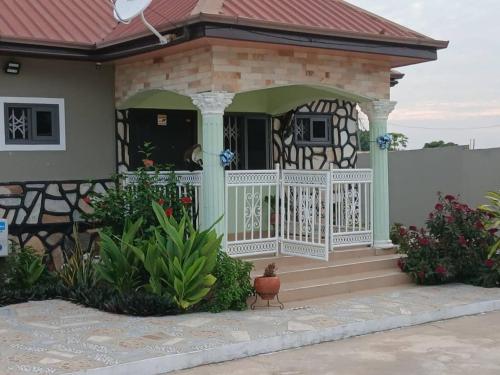 a house with a porch with a white railing at Madora Lodge in Tafi Atome