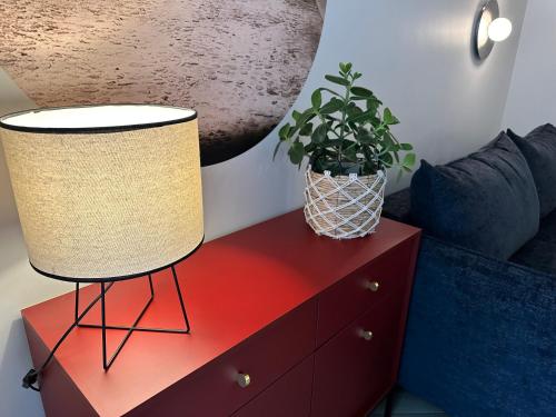 a lamp on a red dresser with a plant on it at NOWE !!! Apartamenty OFF PIOTRKOWSKA w Roosevelta Residence, Klimatyzacja, Wejście na KOD, WiFi, FV in Łódź