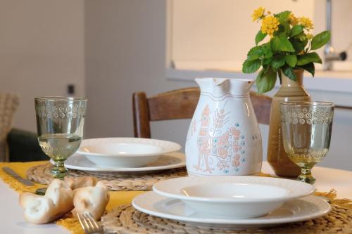 a table with plates and glasses and a vase at Su Scannu - Stylish Beach apartment with Lounge terrace in Quartu Sant'Elena