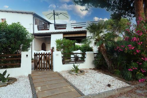 a white house with a fence and some flowers at Su Scannu - Stylish Beach apartment with Lounge terrace in Quartu Sant'Elena