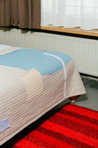 a bed with a blanket on top of a red rug at JAM Brussels in Brussels