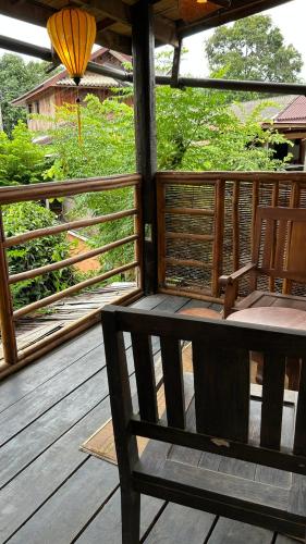 a wooden porch with a bench on a deck at Sa Sa Lao in Luang Prabang