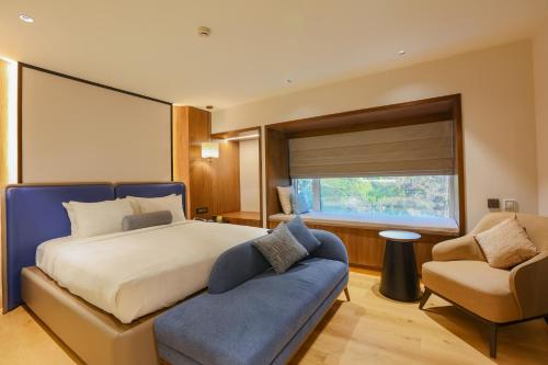 a bedroom with a bed and a couch and a window at Pride Hotel Pune in Pune