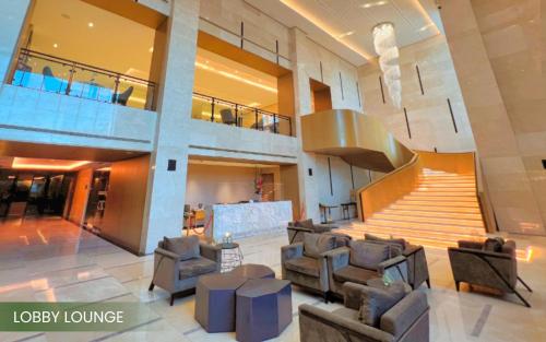 a lobby of a building with couches and a staircase at Acacia Hotel Davao in Davao City