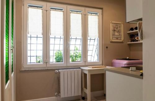 a kitchen with three windows and a white radiator at RRooms-Locazione Turistica in Monterotondo