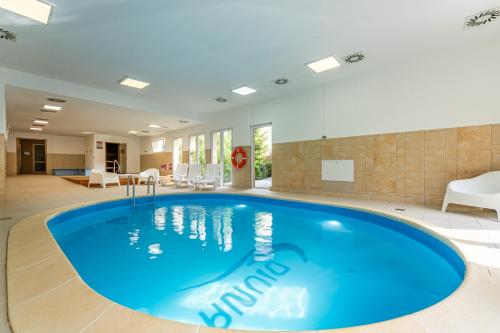 a large blue pool in a room with chairs at DIUNA Beskidy - Korbielów in Korbielów
