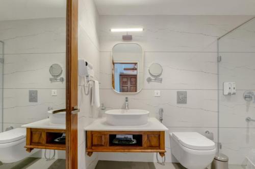 a bathroom with a sink and a toilet and a mirror at Le Montfort Resort in Munnar