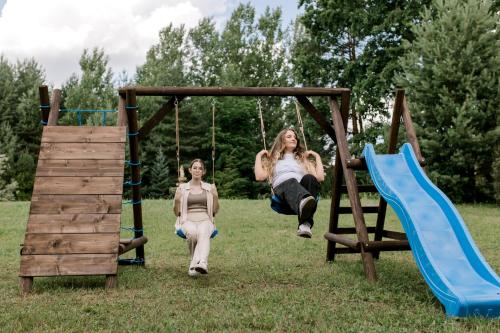 two girls playing on a swing in a park at Starodawna Chata - Dziad in Zamość