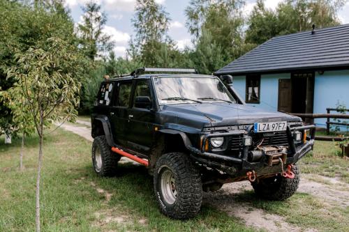 a black jeep parked in the grass near a house at Starodawna Chata - Dziad in Zamość