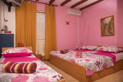 two beds in a room with pink walls at Apartman Katarina in Dramalj