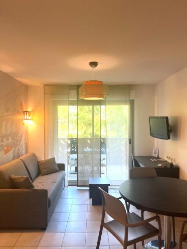 a living room with a couch and a table at Lagrange Aparthotel Montpellier Millénaire in Montpellier