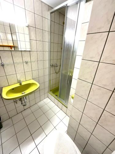 a bathroom with a yellow sink and a shower at Hotel Wildrose in Neukirchen am Großvenediger