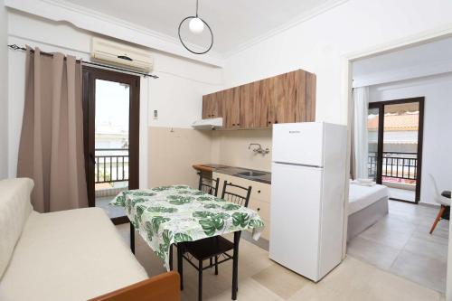 a kitchen with a table and a white refrigerator at Stratos Angels apartments in Pefkohori