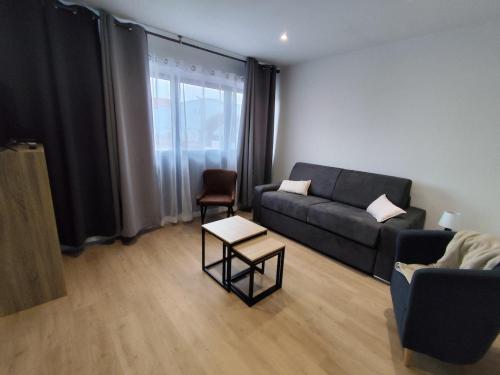 a living room with a couch and a table at Le sable fin, proche mer, calme et détente in Quend-Plage