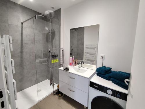 a bathroom with a shower and a sink and a washing machine at Le sable fin, proche mer, calme et détente in Quend-Plage