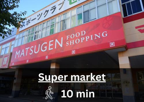 a store with a red sign on the side of a building at Transit Hostel in Izumi-Sano