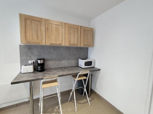 a kitchen with a counter with two stools at Le sable fin, proche mer, calme et détente in Quend-Plage
