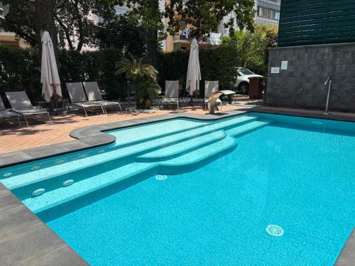 a large blue swimming pool with chairs and umbrellas at Alhambra "Etna Charme" - Guest House in Giarre