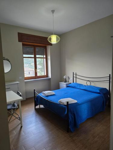 a bedroom with a blue bed and a desk and a window at B&B Camposauro in Vitulano