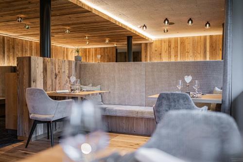a restaurant with tables and chairs and a bench at Hotel Laurin in Dobbiaco