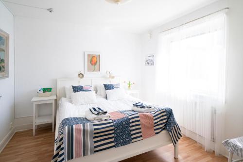 a white bedroom with a bed with a striped blanket at Pensionat Strandgården in Mölle