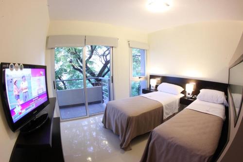 um quarto de hotel com duas camas e uma televisão de ecrã plano em Lecer Apart em Buenos Aires
