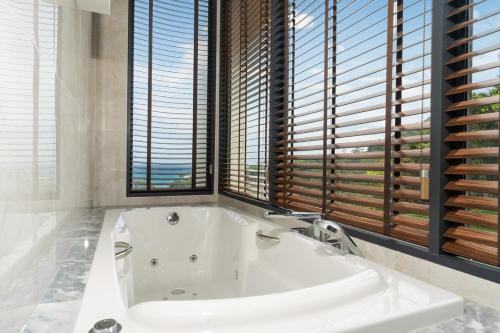 a white bath tub in a bathroom with windows at The Exclusive Sky D1 豪华4卧室海景别墅 私人12m无边海景泳池 每日清洁 in Kamala Beach
