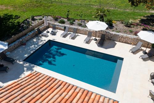 une vue aérienne d'une piscine avec chaises et parasols dans l'établissement Le Domaine de la Haye - Gîtes, à Saint-Christophe-du-Bois