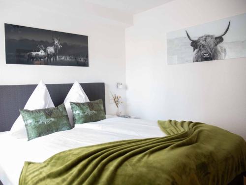 a bedroom with a bed with a green blanket on it at Am 12er in Mittelberg