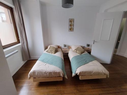 MirecourtにあるAppartement Mirecourt Centreの窓のある小さな部屋にベッドが2つある